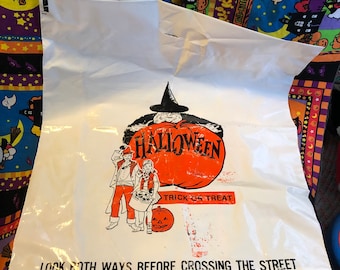 Könnte beinhalten: Eine weiße Plastiktüte für Süßigkeiten mit einer Grafik einer Hexe, einem großen orangefarbenen Kürbis und zwei Kindern. Der Text lautet HALLOWEEN, TRICK OR TREAT und LOOK BOTH WAYS BEFORE CROSSING THE STREET in schwarzer und oranger Schrift.
