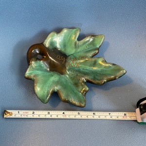 May include: A green and brown ceramic leaf-shaped dish with the words "Algonquin Park" written in gold lettering.