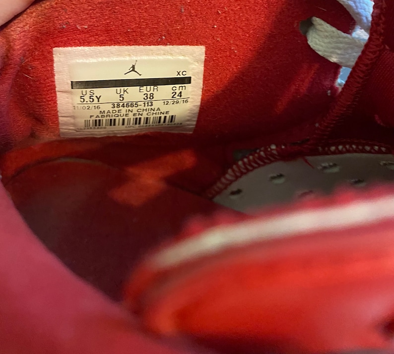 May include: A red shoe size tag with the text "US 5.5Y UK 5 EUR 38 cm 24 11/02/16 384665-113 MADE IN CHINA FABRIQUE EN CHINE 12/29/16"