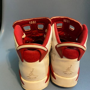 May include: A pair of white and red sneakers with the text "1991" on the back of each shoe.