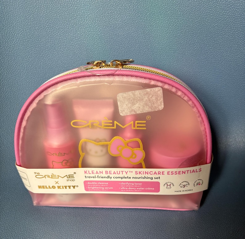 May include: A pink Hello Kitty travel-sized skincare set in a clear plastic pouch with a zipper. The set includes a cleanser, toner, and moisturizer. The pouch has the text "KLEAN BEAUTY&trade; SKINCARE ESSENTIALS" and "travel-friendly complete nourishing set".