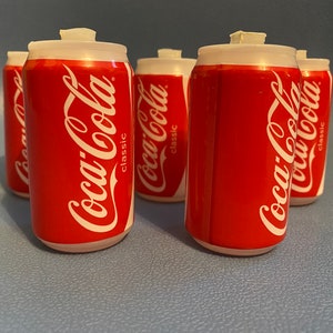May include: Four red and white Coca-Cola cans with the words "Coca-Cola classic" printed on them.