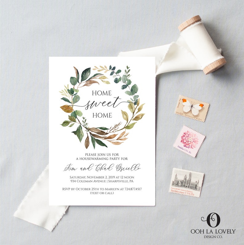 May include: A white invitation card with the text "Home Sweet Home" inside a watercolor wreath of green and brown leaves. The card includes details for a housewarming party, with a roll of white ribbon and decorative stamps.