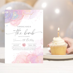 May include: A birthday invitation with watercolor-style pink, purple, and gold accents. The text reads "Turning Nine is the bomb" and includes the date August 17th. A cupcake with a lit candle sits on a plate.