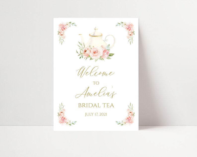 May include: A white sign with gold script that reads "Welcome to Amelia's Bridal Tea July 17, 2021." The sign features a watercolor illustration of a teapot and pink roses. Floral corner accents frame the text.