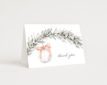 Könnte beinhalten: Gefaltete weiße Karte mit Aquarelldesign. Das Design zeigt einen hängenden Glasornament mit einer pfirsichfarbenen Schleife, eine grün-weiße Blumengirlande und die Worte "thank you" in Schreibschrift.