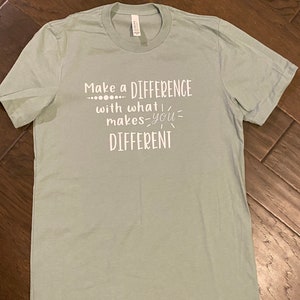 Può includere: Una maglietta blu chiaro con la scritta "Make a DIFFERENCE... with what makes you DIFFERENT" stampata in bianco.