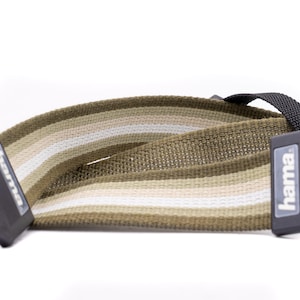 May include: A brown and beige striped camera strap with black adjustable buckles and the word "hama" printed on one of the buckles.