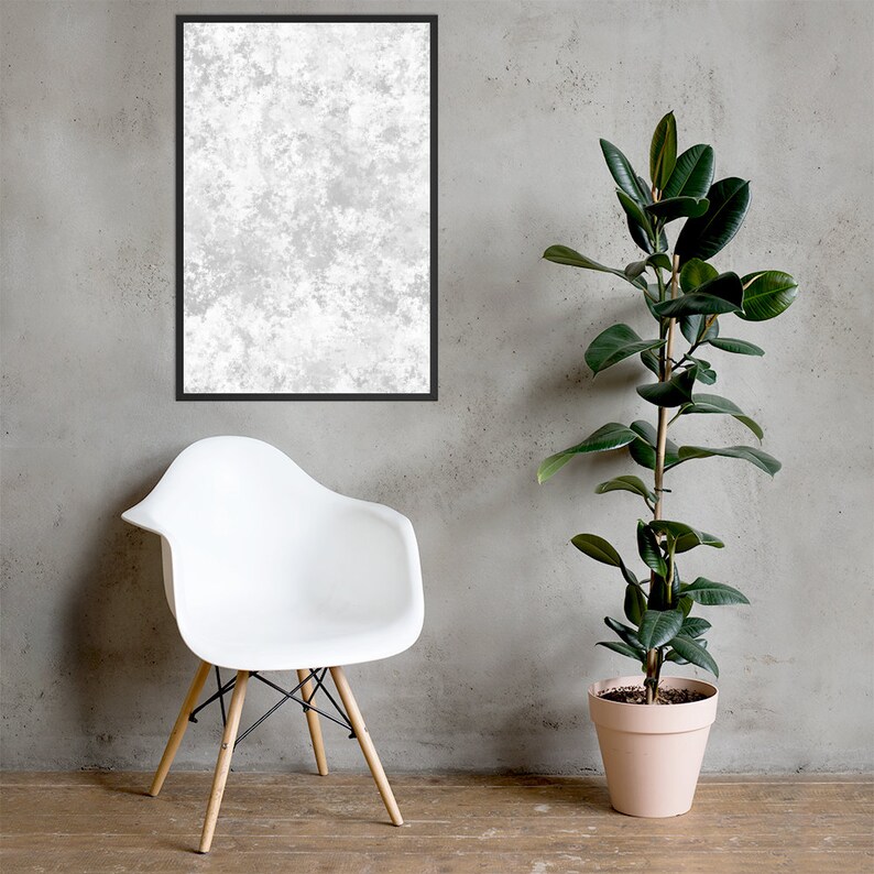 May include: A white chair with wooden legs sits in front of a gray wall. A potted plant with green leaves is on the right side of the image. A framed abstract print with a white and gray design hangs on the wall.