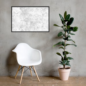 May include: A white chair with wooden legs sits in front of a gray wall. A potted plant with green leaves is on the right side of the image. A framed picture with a white textured background hangs on the wall.