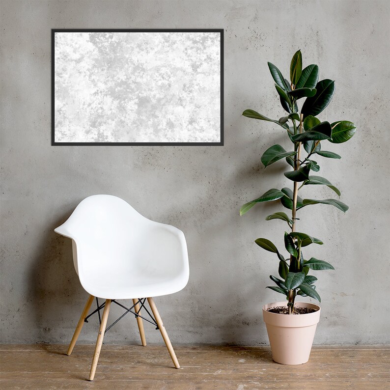 May include: A white chair with wooden legs sits in front of a gray wall. A potted plant with green leaves is on the right side of the image. A framed picture with a white textured background hangs on the wall.