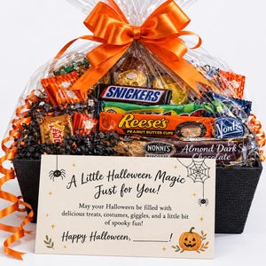 May include: A black basket filled with assorted candy bars including Snickers, Reese's, and Nonni's biscotti, wrapped in clear cellophane with an orange ribbon. A card reads: A Little Halloween Magic Just for You! May your Halloween be filled with delicious treats, costumes, giggles, and a little bit of spooky fun! Happy Halloween, ______!