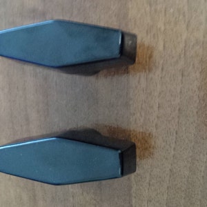 May include: Two black plastic cabinet knobs with a hexagonal shape.