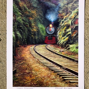 Pode incluir: Uma locomotiva a vapor vintage emerge de uma floresta verdejante e exuberante, com sua fumaça subindo no ar. Os trilhos do trem curvam-se suavemente pela floresta, criando uma cena pitoresca. A obra de arte é intitulada "Steam Excursion" e assinada pela artista, Jeanette Norman.