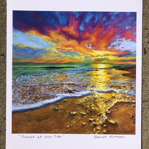 May include: A painting of a sunset over the ocean with a sandy beach in the foreground. The sky is a mix of orange, pink, and purple. The water is a deep blue and the waves are crashing on the shore. The painting is signed "Jennet Norman" and titled "Sunset at Low Tide".