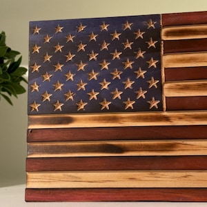May include: A wooden American flag with a distressed finish. The stars are blue and the stripes are red and white.