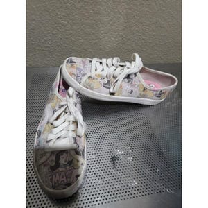 Può includere: Un paio di scarpe da ginnastica in tela bianca con grafica in stile fumetto in vari colori. Le scarpe hanno lacci bianchi e una suola in gomma bianca. La punta di una scarpa presenta la parola "SMACK".