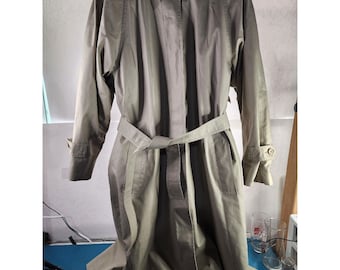 Puede incluir: Una gabardina larga de color verde oliva con cinturón y cierre de botones. La gabardina tiene un diseño clásico y está hecha de una tela suave y ligera.