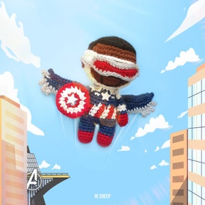 Puede incluir: Un juguete de amigurumi tejido a crochet de un superhéroe que lleva un traje rojo, blanco y azul con un escudo en forma de estrella. El juguete está volando en el aire con un horizonte de ciudad en el fondo.