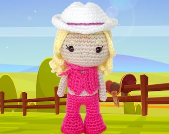 Peut inclure: Une poupée en crochet portant un chapeau de cow-boy blanc, un gilet rose et un pantalon rose. La poupée a les cheveux blonds et les yeux bruns. La poupée est debout devant une clôture en bois.