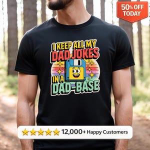 May include: Black t-shirt with the text "I KEEP ALL MY DAD JOKES IN A DAD-BASE" in a colourful design featuring a floppy disk with a smiling face. The shirt also has a "50% OFF TODAY" banner and a customer satisfaction rating.