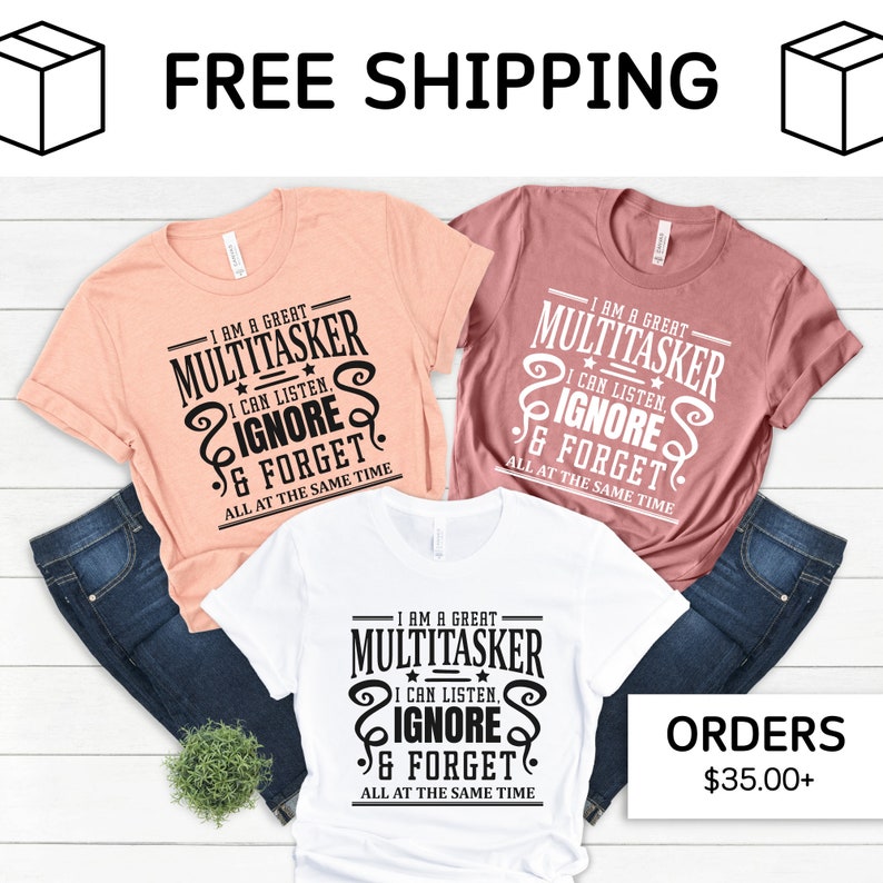 May include: Three t-shirts with a humorous saying about multitasking. The shirts are in white, peach, and pink. The text on the shirts reads "I am a great multitasker. I can listen, ignore, and forget all at the same time."