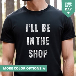 以下が含まれることがあります： 白い文字で「I'll be in the shop」と書かれた黒いTシャツです。