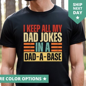 May include: Black t-shirt with a vintage-style graphic that says "I keep all my dad jokes in a dad-a-base".