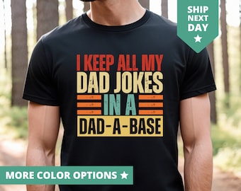 May include: Black t-shirt with a vintage-style graphic that says "I keep all my dad jokes in a dad-a-base".
