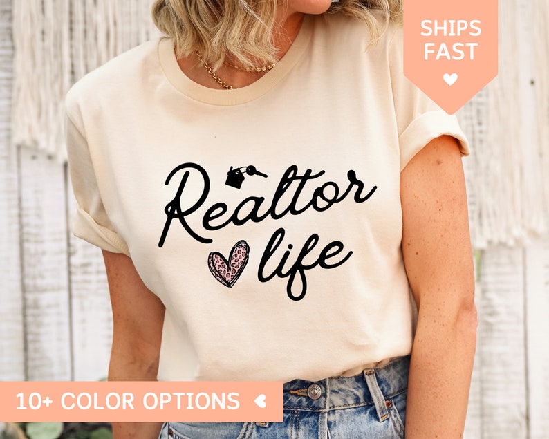 May include: A beige t-shirt with black text that reads "Realtor life" with a pink and black leopard print heart.