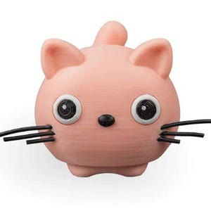 May include: A small, round, light pink cat figurine with a smooth texture. It features two large white eyes with black pupils, a tiny black nose, and three thin black whiskers extending from each side of its face. A small tail points upward.