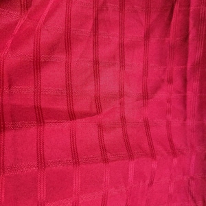 May include: Close-up of a vibrant red fabric with a textured, grid-like pattern. The fabric has a subtle sheen, and the grid is formed by raised, stitched lines. The overall effect is a rich, visually interesting textile, suitable for various applications.
