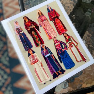 May include: A card with a colorful illustration of nine women wearing traditional clothing from different cultures. The women are all standing in a row and are smiling. The card is printed on a white background.