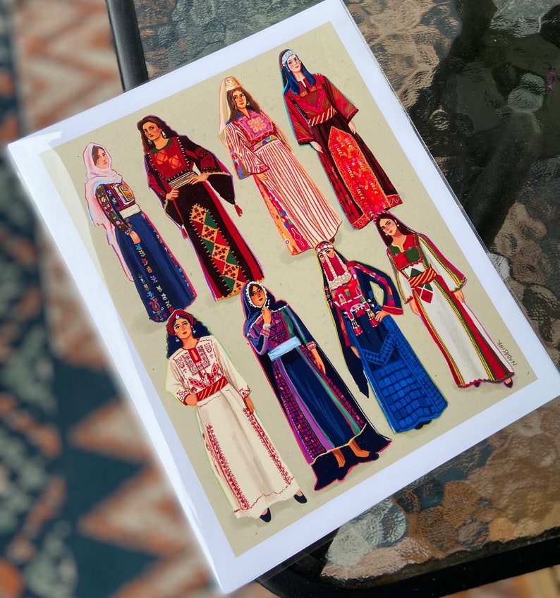 May include: A card with a colorful illustration of nine women wearing traditional clothing from different cultures. The women are all standing in a row and are smiling. The card is printed on a white background.