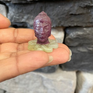 May include: A small, carved, purple jade Buddha figurine with a green jade lotus flower base.