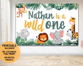 May include: Printable jungle-themed backdrop with the text "Nathan is a wild one" in green and yellow lettering. The backdrop features a variety of jungle animals, including a lion, elephant, giraffe, zebra, and monkey.
