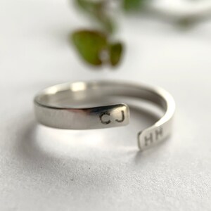 May include: A silver ring with the initials "CJ" and "HN" engraved on the band.