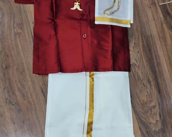 May include: A maroon shirt with a gold chain necklace and a white dhoti with a gold border. The shirt has a button-up collar and short sleeves. The dhoti is a traditional Indian garment worn by men.