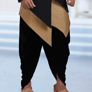 Pu&ograve; includere: Un abito da uomo nero e oro con una parte superiore lunga e asimmetrica e pantaloni di velluto nero. I pantaloni sono raccolti alle caviglie e la parte superiore ha una lunga coda fluida.