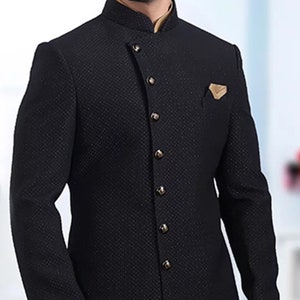 Pu&ograve; includere: Un blazer nero con colletto alla coreana e chiusura con un solo bottone. Il blazer presenta un motivo testurizzato e un orlo diagonale. Il blazer &egrave; indossato sopra una canottiera beige.