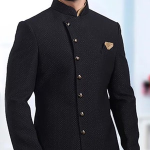 Pu&ograve; includere: Un blazer nero con motivo, colletto alto e chiusura con un solo bottone. Il blazer ha un orlo lungo e asimmetrico e un fazzoletto da taschino dorato.