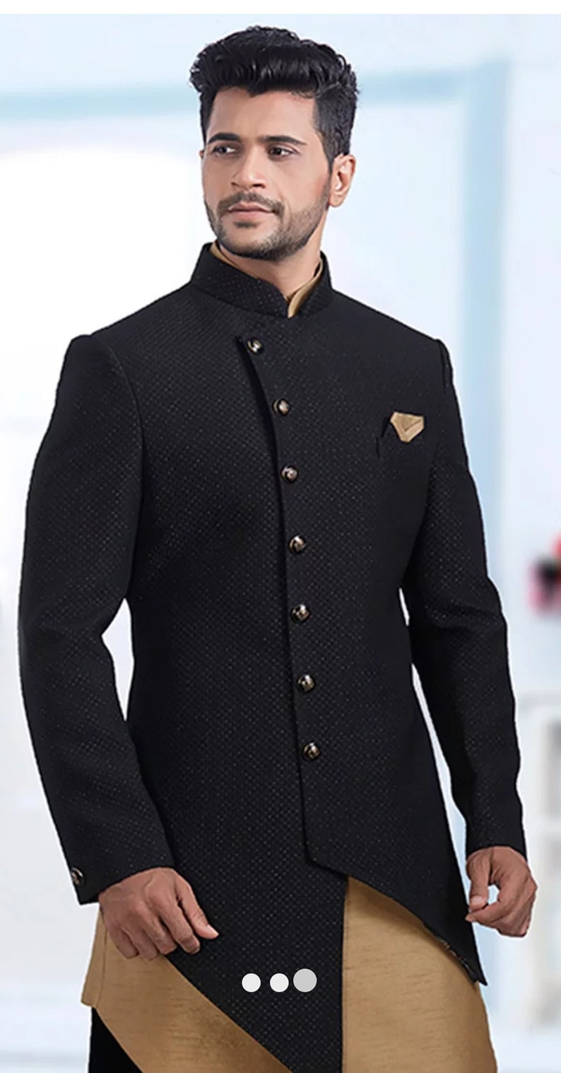 Pu&ograve; includere: Un blazer nero con motivo, colletto alto e chiusura con un solo bottone. Il blazer ha un orlo lungo e asimmetrico e un fazzoletto da taschino dorato.