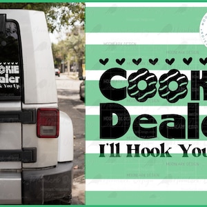 May include: A white Jeep with a black and white sticker that says "Cookie Dealer I'll Hook You Up". The sticker has a graphic of two cookies with white frosting and chocolate chips.