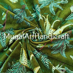 May include: Green velvet fabric with a printed design of stylized animals and plants. The fabric has a soft, plush texture and is perfect for upholstery or crafting projects.
