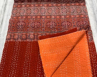 Op de afbeelding: Een rood en oranje kantha-deken met een bloemenpatroon. Het deken is gemaakt van katoen en met de hand gestikt. Het is een traditioneel Indiaas textiel.