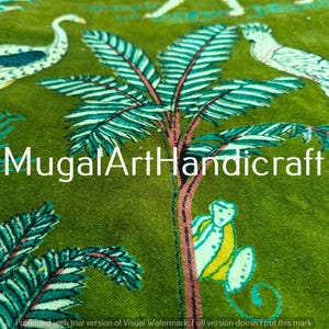May include: Green fabric with a white and blue floral pattern. The pattern includes palm trees, birds, and other floral designs. The fabric has the text "MugalArtHandicraft" printed on it.