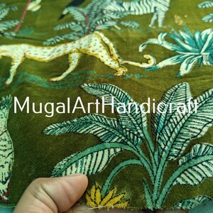 May include: Green velvet fabric with a printed design of leopards, zebras, and tropical plants. The fabric has a textured surface and a subtle sheen. The text "MugalArtHandicraft" is printed on the fabric.