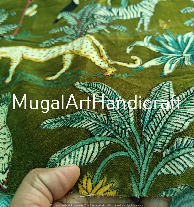 May include: Green velvet fabric with a printed design of leopards, zebras, and tropical plants. The fabric has a textured surface and a subtle sheen. The text "MugalArtHandicraft" is printed on the fabric.