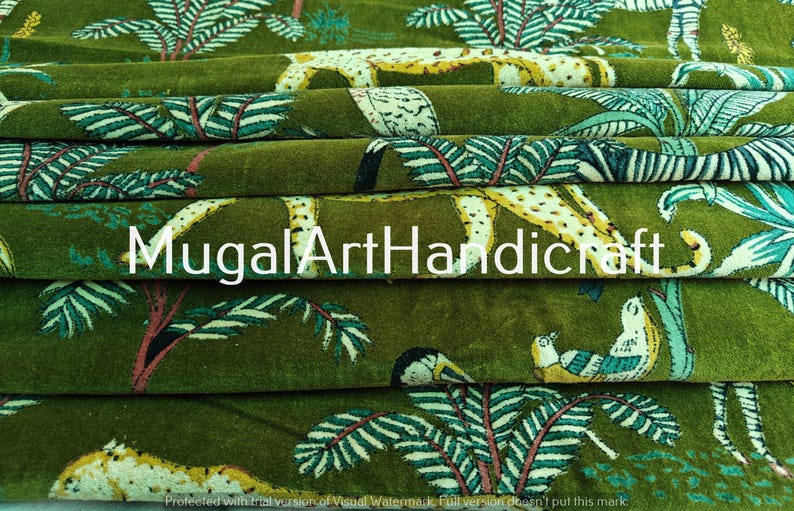 May include: Green fabric with a repeating pattern of leopards, birds, and leafy branches. The fabric has a velvet texture and is folded in layers. The text "Mugal Art Handicraft" is visible in the center of the image.