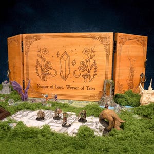 Puede incluir: Una pantalla de juego de mesa de madera con diseños florales y de cristal grabados, y el texto "Keeper of Lore, Weaver of Tales". La pantalla está rodeada de figuras en miniatura, dados y una figura de dragón, sobre una superficie de musgo verde.